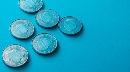 Coins arranged on blue background, showcasing their shiny surfaces and intricate designs. image conveys sense of value and currency