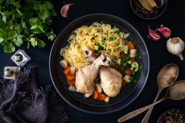 Broth - chicken soup with noodles and vegetables on black table