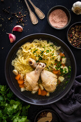 Broth - chicken soup with noodles and vegetables on black table