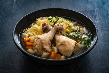 Broth - chicken soup with noodles and vegetables on black table