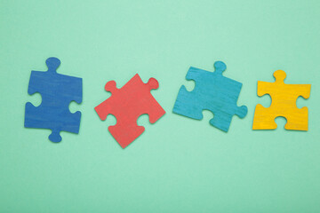 Obraz premium Colorful puzzle on mint background. Multi-colored heart as a symbol of World Autism Awareness Day. Top view