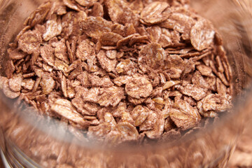 Dry oat flakes with organic cocoa powder in a glass container. Macro shot.