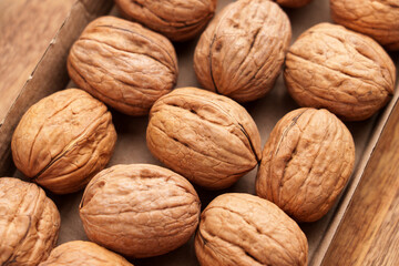 Group of raw walnuts in biodegradable cardboard packaging on wooden table. Organic food. Top view