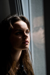 Fototapeta premium Close up portrait of dreaming girl. Teem imagining near window. Little dreamer. Imaginative girl. Dreamy teenager looking up. Teen face. Teenager girl with a dreamy expression. Thoughtful teen.