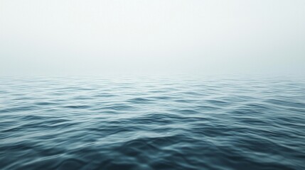 Obraz premium Early morning light casts a soft glow over the tranquil ocean, where gentle waves weave a rhythm across the surface. A thin mist hangs in the air, enhancing the peaceful ambiance