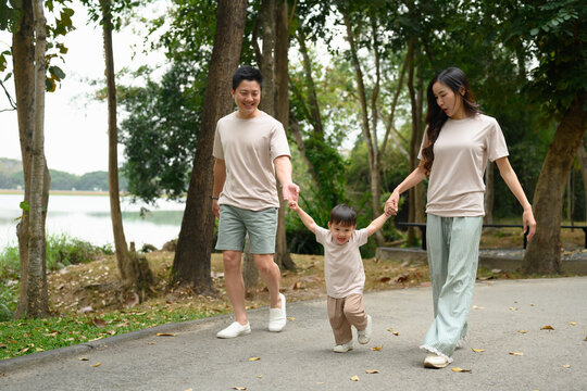 Happy family walking together along a park path, holding hands