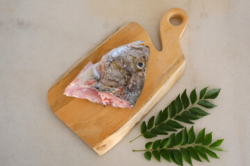 Raw golden snapper heads ready for cooking with some spices on wooden cutting board