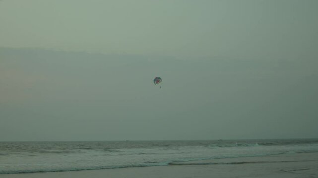 Parasailing over the ocean with a tranquil sky and calm waters in the background