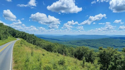 Obraz premium Mountain Road Winding Through Lush Green Landscape Under Blue Sky