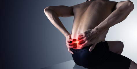 Man holding both hands on lower back pain ,inflamed backache with copy space.