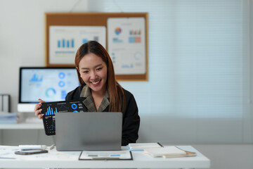 Young cheerful asian businesswoman showing charts and graphs on tablet during video conference on laptop, presenting financial report to client or investor