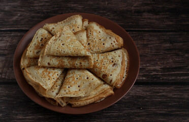 Bake openwork pancakes in a hole triangles on a plate on a dark background