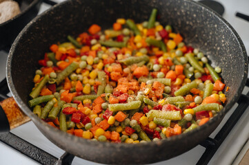 A frying pan with asparagus, carrots, green peas, corn, and peppers. Perfect for themes of healthy food, cooking, and nutrition