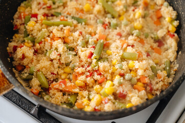 A frying pan filled with couscous and colorful vegetables. Ideal for themes of healthy eating, cooking, and Mediterranean cuisine