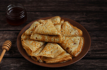 Baking openwork pancakes in a hole triangles on a plate on a dark background with honey