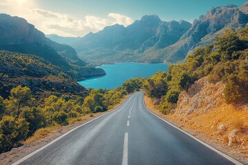 Fototapeta premium Cyclist climbs a winding road through scenic mountains and coastal views at dawn