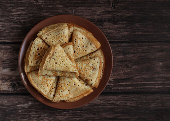 Bake openwork pancakes in a hole triangles on a plate on a dark background