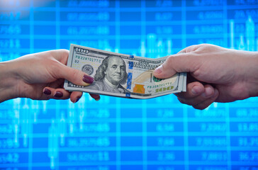 Hands exchanging US dollar bills against a financial data background.