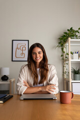 Young female entrepreneur at home office. Woman looking at camera sitting at desk. Vertical image.