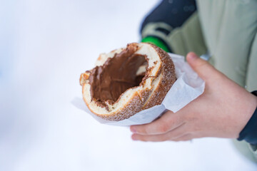 Traditional Czech trdelnik with chocolate filling held by a child in winter