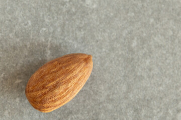 An almond close-up on a grey surface.