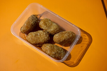 Gemblong, Indonesian sweet snack, in a clear plastic container on an orange surface.