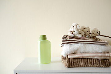 Laundry, washing and cleaning concept. Stack of clean clothes, with various detergents - gels laundry on light background, copy space