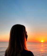 a woman watching a sunset on a torpical beach generated with artificial intelligence