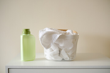 Washing gel or laundry detergent near laundry basket with towels on white background. Mock up, copy space.