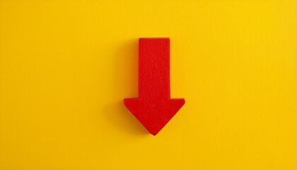 Red wooden arrow pointing down on yellow background. Business, market decline or economic.