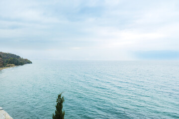 Vast Tranquil Lake Horizon Under Soft Cloudy Sky with Distant Mountains
