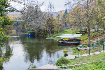 A tranquil scene of a lake with boats docked at the shore. Lush greenery surrounds the water's edge, creating a serene and picturesque setting.