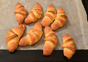 Freshly baked croissants cooling on a baking tray in a kitchen setting during the afternoon
