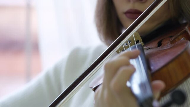 Woman playing violin swiftly with bow, using musical skills. Female fiddler refining music technique, focused classical practice, fast bow strokes, violin mastery with precision, sound performance