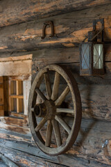 Obraz premium Wooden wheel and kerosene lamp on the walls of a log barn