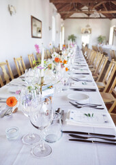 Banquet table in rustic European style. White tablecloth and empty glasses and plates..