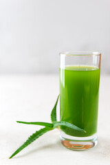 Aloe vera leaves and aloe vera juice in glass on table. Vertical orientation.
