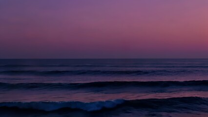 Fototapeta premium Deep blue waves rolling across vast ocean surface, twilight painting sky with purple, pink, orange gradient. Sea sunset concept