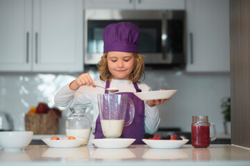 Chef kid preparing tasty food at kitchen. Kid chef cook is learning how to make a cake in the home...
