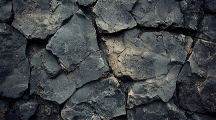 Fototapeta premium Dark grey stone wall with rough texture forming a natural background