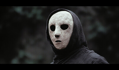 Enigmatic Hooded Figure with Textured Mask Invokes Mystery and Intrigue