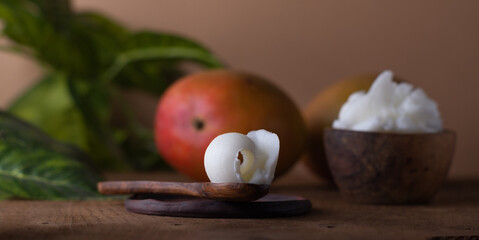 Mango butter and fresh ripe mango on a wooden table. Organic cosmetics, skin care, spa concept.