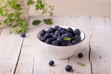 Fresh organic blueberries in a white bowl on wooden background.