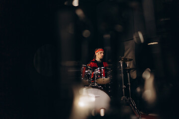Young Drummer With Red Bandana Playing Drums in a Dark Music Studio