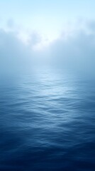 Obraz premium A serene view of rippling waters appearing calm and tranquil under a soft blue sky, with mist gently rising from the surface, creating a peaceful and reflective atmosphere.