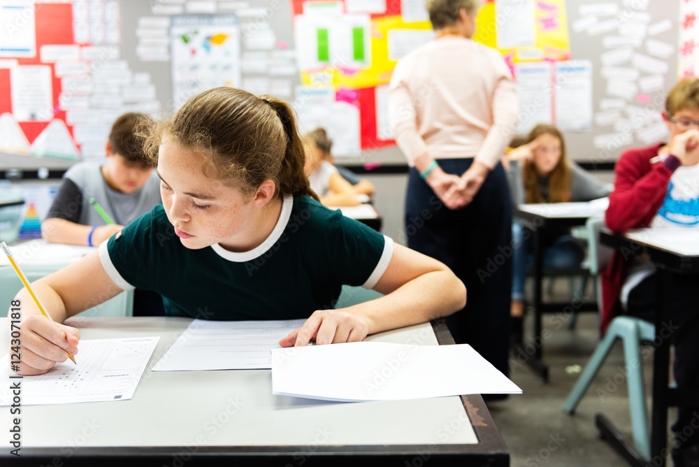 Poster students in a classroom focusing on their work. a girl in the foreground writes diligently. classroo