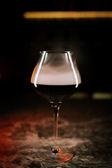 Elegant glass of red wine with smoke swirling around it on a dark surface during an evening setting