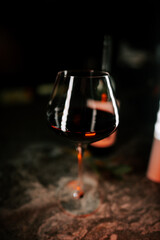 Red wine glass reflecting ambient light in a dimly lit bar during evening hours