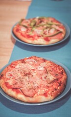 Beautiful shot of two pizzas with bacon on the blue plates