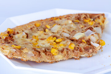 Closeup shot of a piece of a tasty Italian pizza with meat and vegetables on a white plate